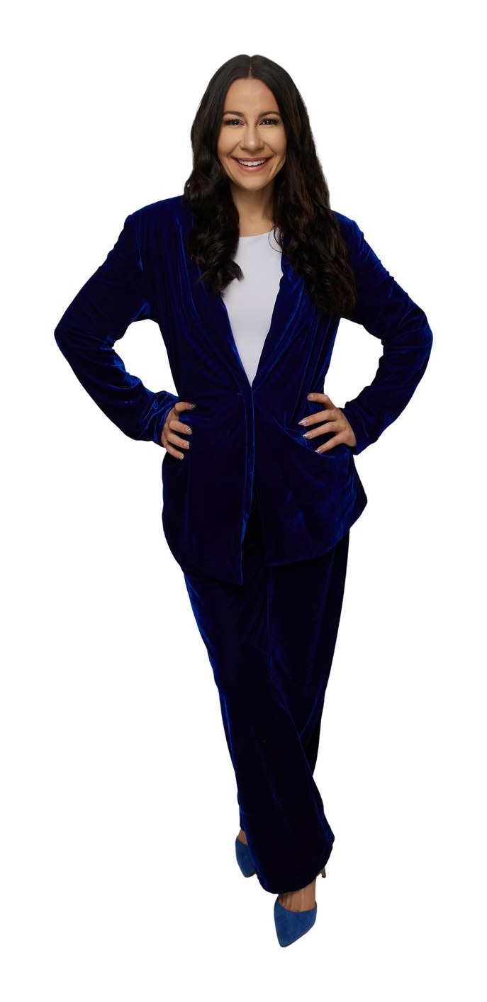 Bryanna Baptiste in a royal blue velvet suit with her hands on her hips, on a white background
